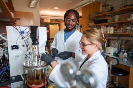 Two students work in a lab using advanced instrumentation.